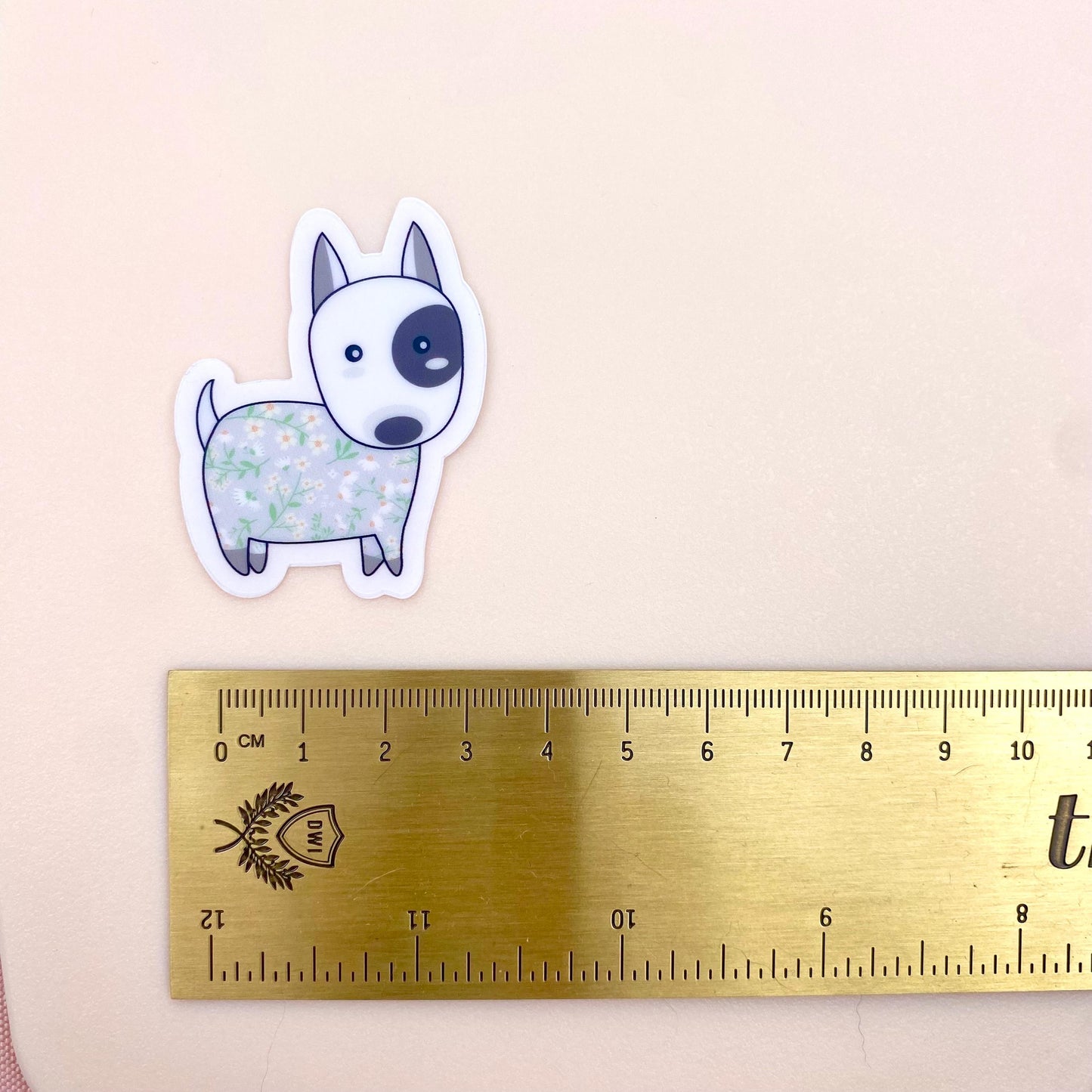 Sticker of a dog with floral pattern next to a ruler on a beige background