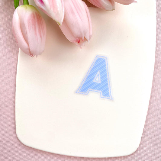A blue striped letter 'A' sticker against a white background with pink tulips