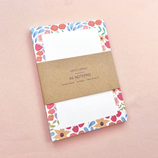 A6 notepad with floral border design on a pink background