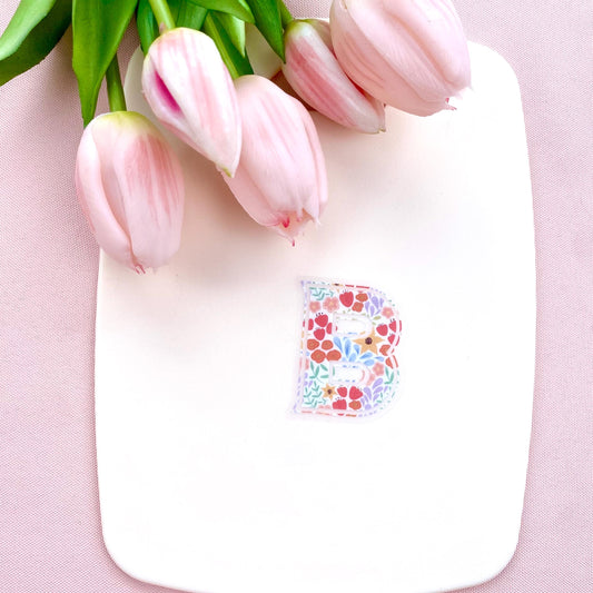 Pink tulips on a white board with a floral letter 'B' sticker on a pink background