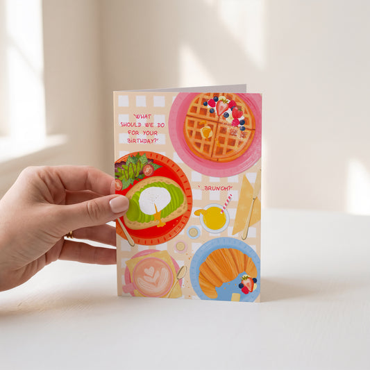 Colourful card with illustrations of brunch food items held by a hand against a light background