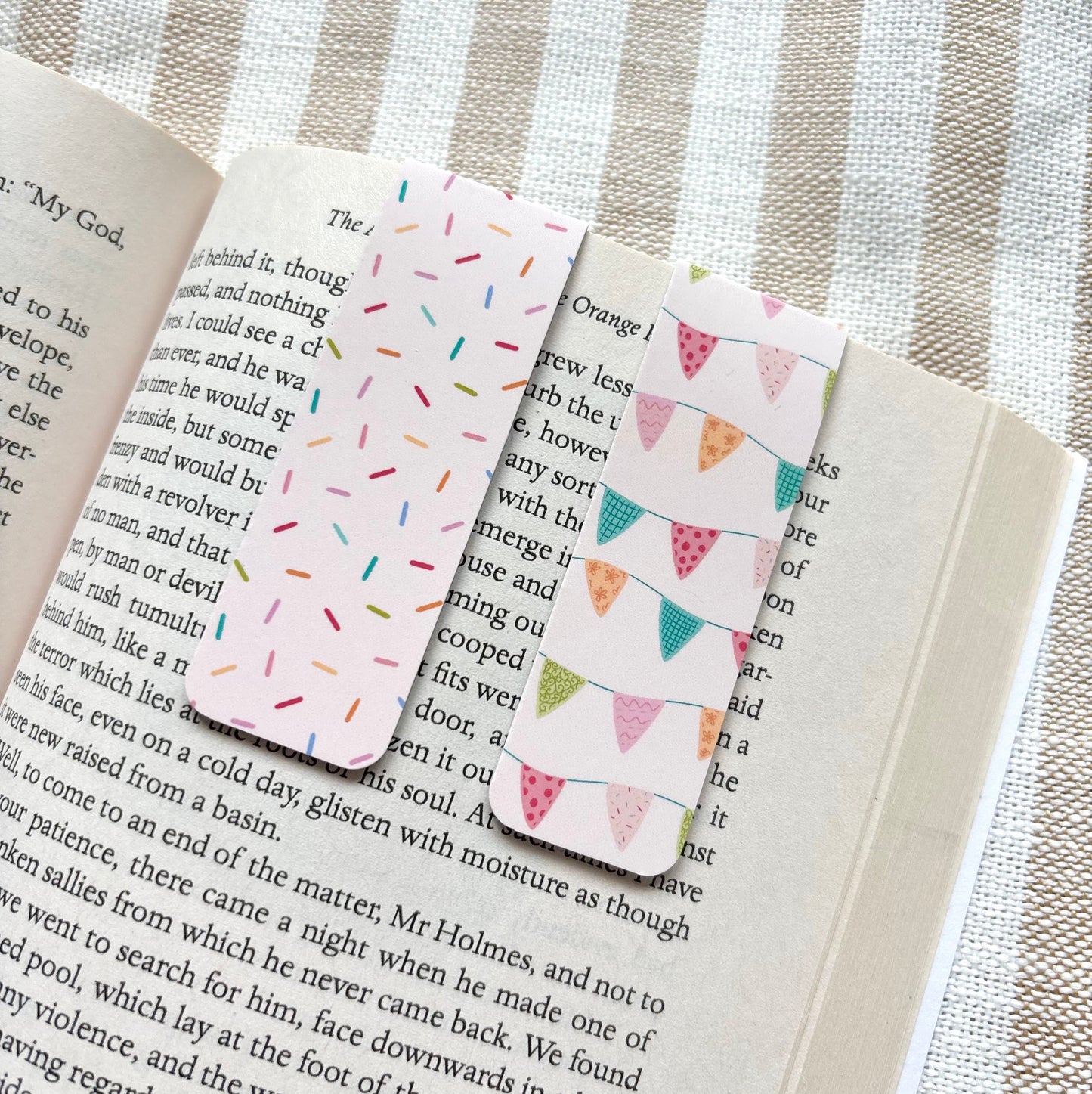 Two patterned bookmarks on an open book with a striped fabric background