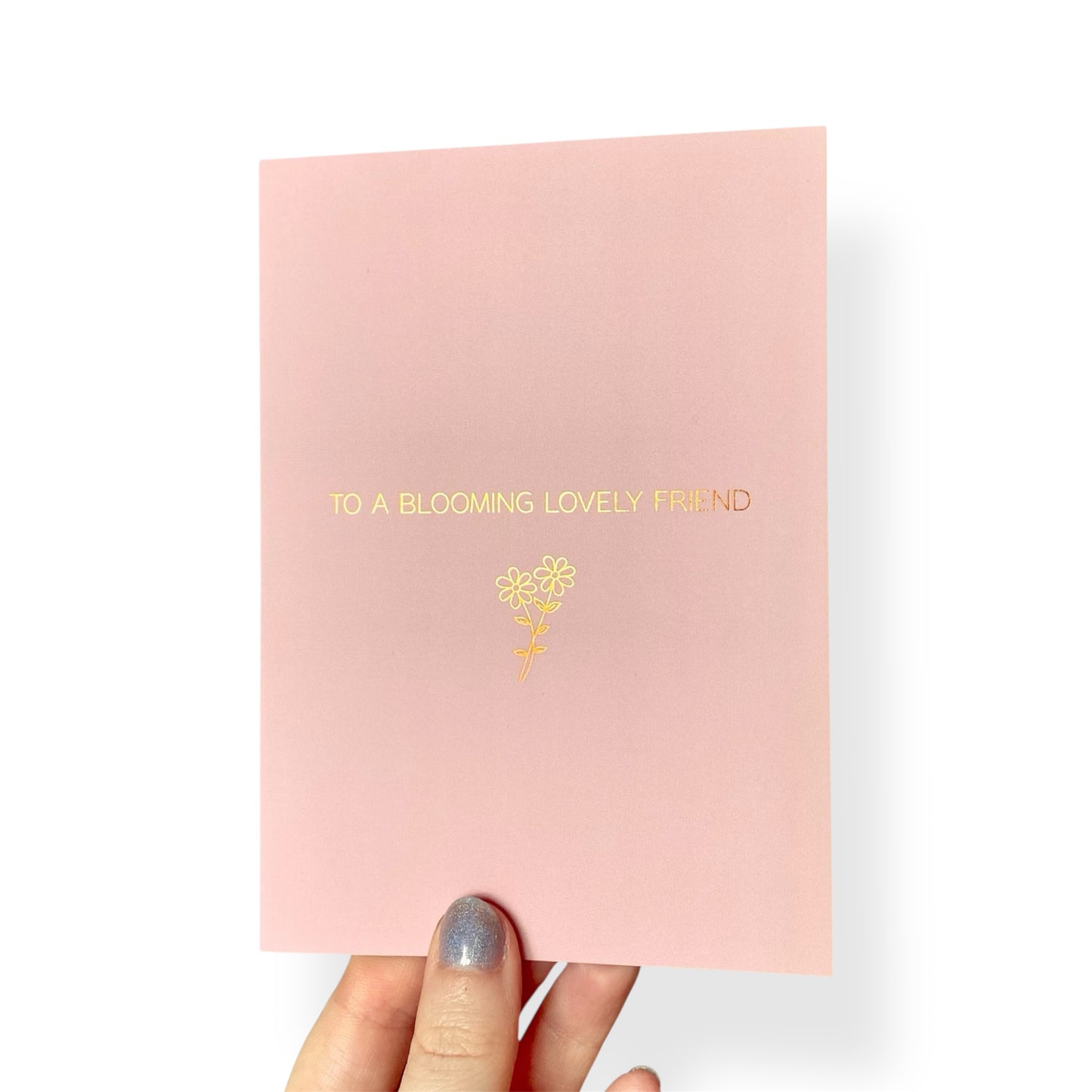 A simple pink card with ‘For a blooming lovely friend’ in rose gold text and a foiled flower outline.