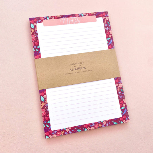 Floral notepad with a brown kraft paper label on a pink background
