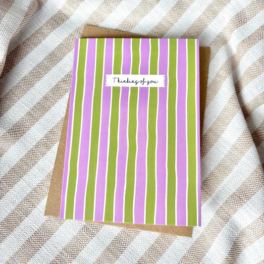 Striped card with 'Thinking of you' text on a striped fabric background