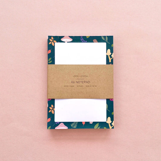 Notepad with mushroom and leaf patterned border on a pink background