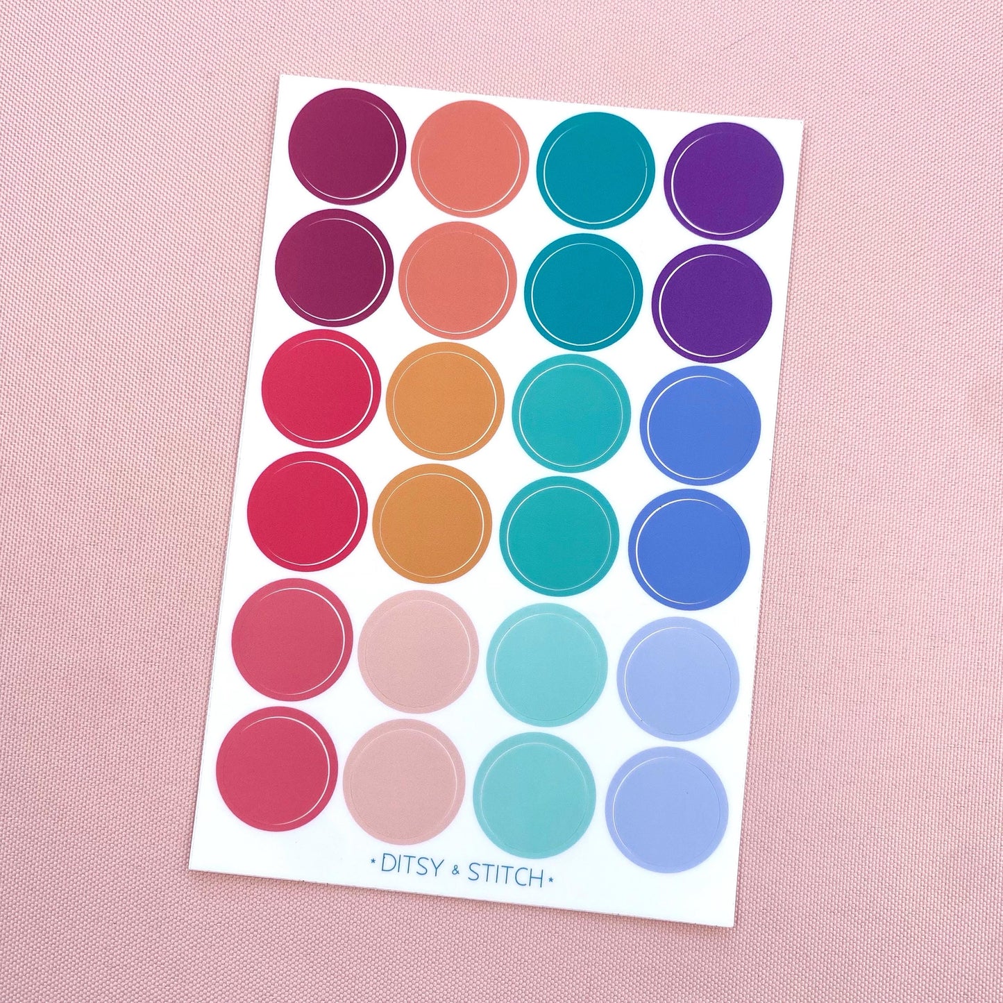 Sheet of colorful dot stickers on a pink background