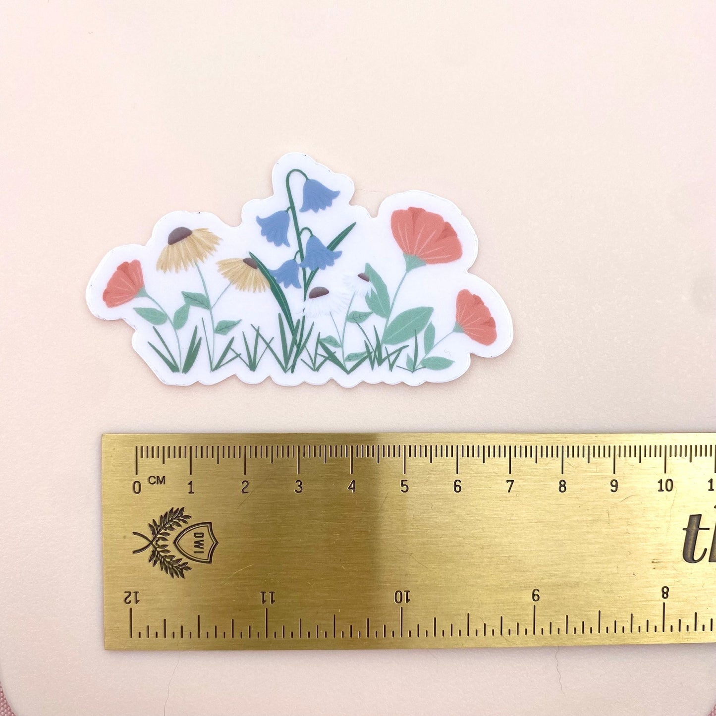 Floral sticker with a ruler for scale on a beige background