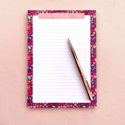 Floral notepad with a pen on a pink background
