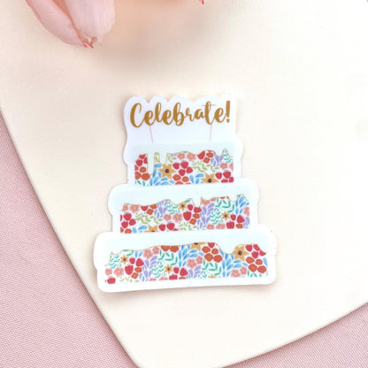 Decorative sticker with floral cake design and 'Celebrate!' text on a pink background