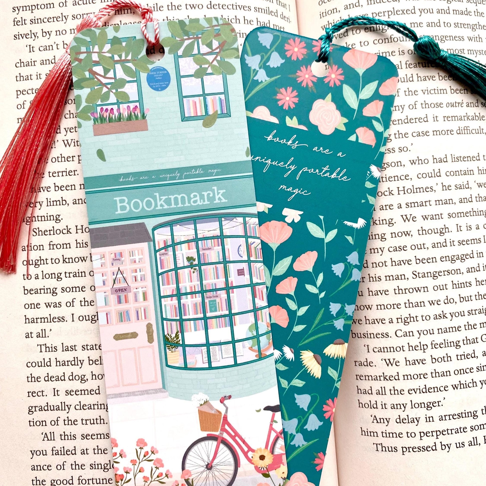 Two colourful bookmarks with tassels against an open book, one showing the front and the other showing the back