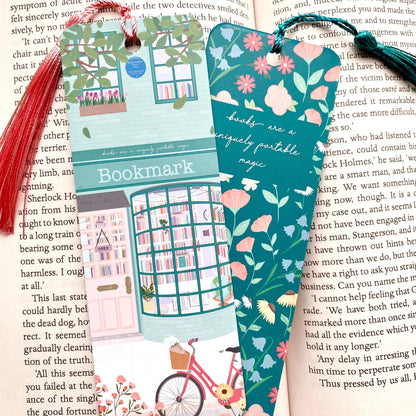Two colourful bookmarks with tassels against an open book, one showing the front and the other showing the back