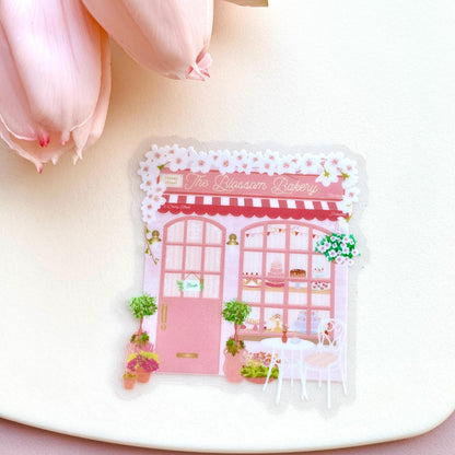 Sticker of a bakery design on a white surface with pink flowers.