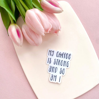 A transparent sticker with 'My coffee is strong and so am I' text against a white background with pink tulips