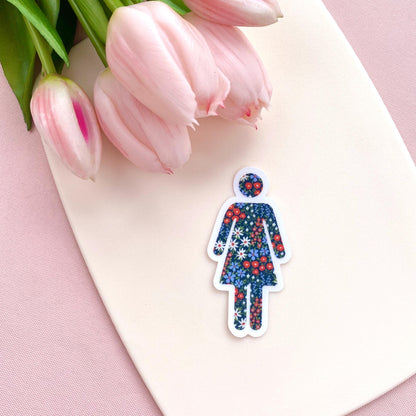 Floral-patterned woman symbol sticker on a pink surface with tulips
