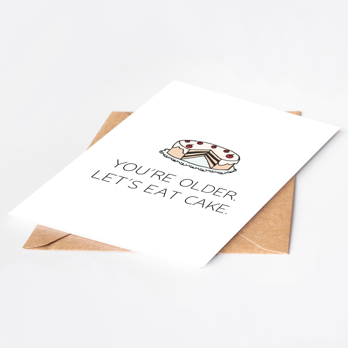 Greeting card with cake illustration and text 'You're older. Let's eat cake.' on a white background.