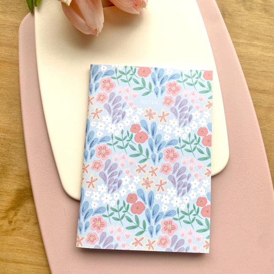 Floral patterned notebook on a pink surface with a wooden background