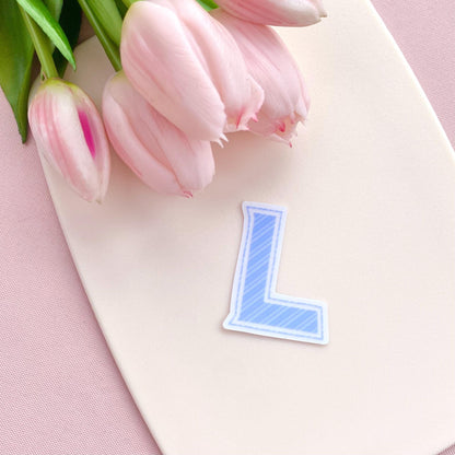 Pink tulips on a white board with a blue letter 'L' sticker on a pink background