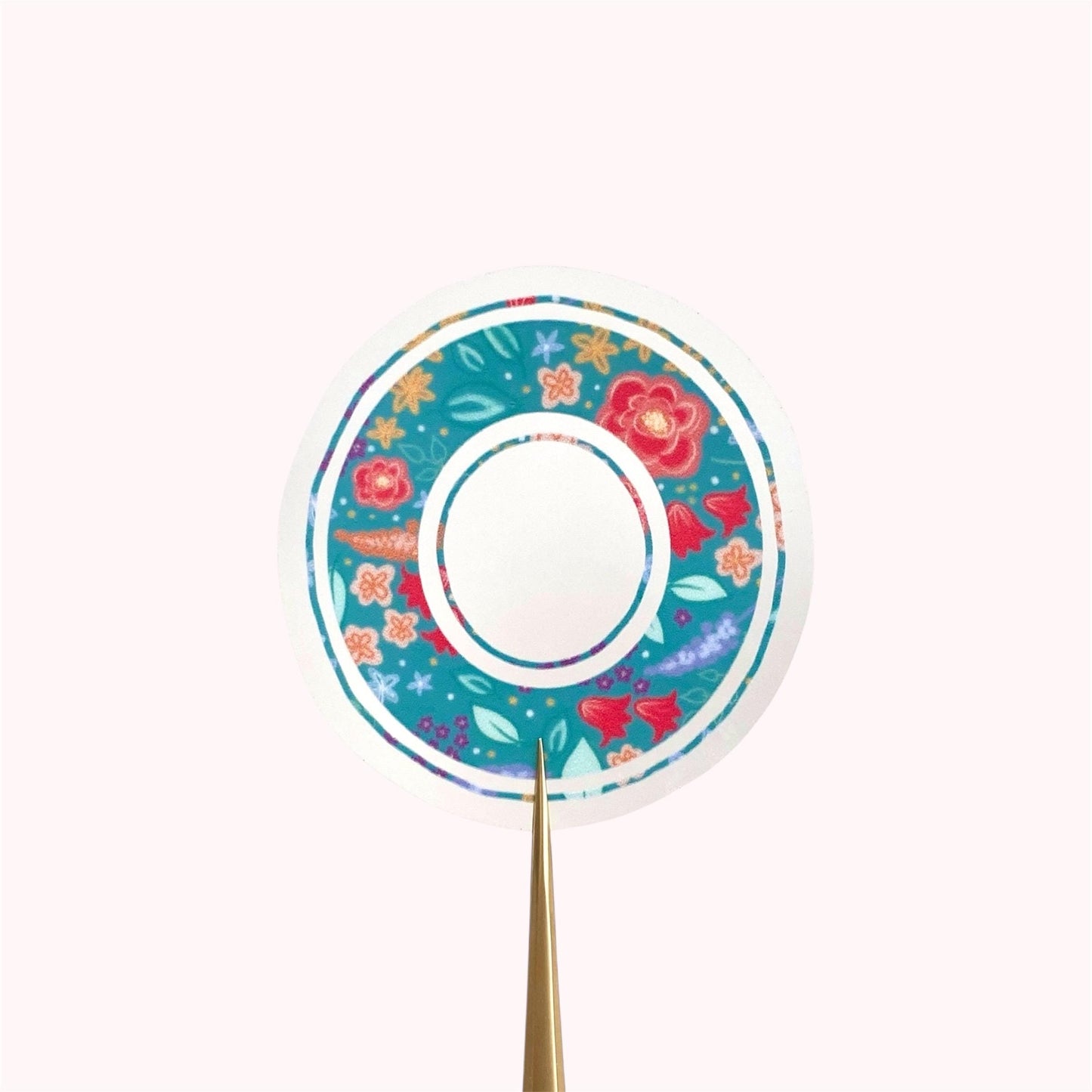 Decorative letter 'O' sticker with floral pattern held on a white background