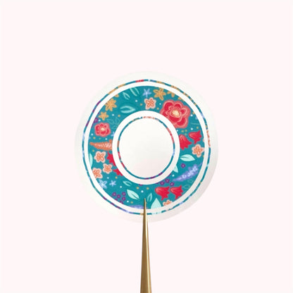 Decorative letter 'O' sticker with floral pattern held on a white background