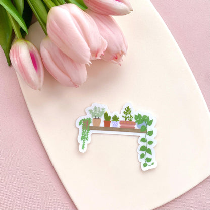 A transparent vinyl sticker with an illustration of a wooden shelf with potted plants on a white background