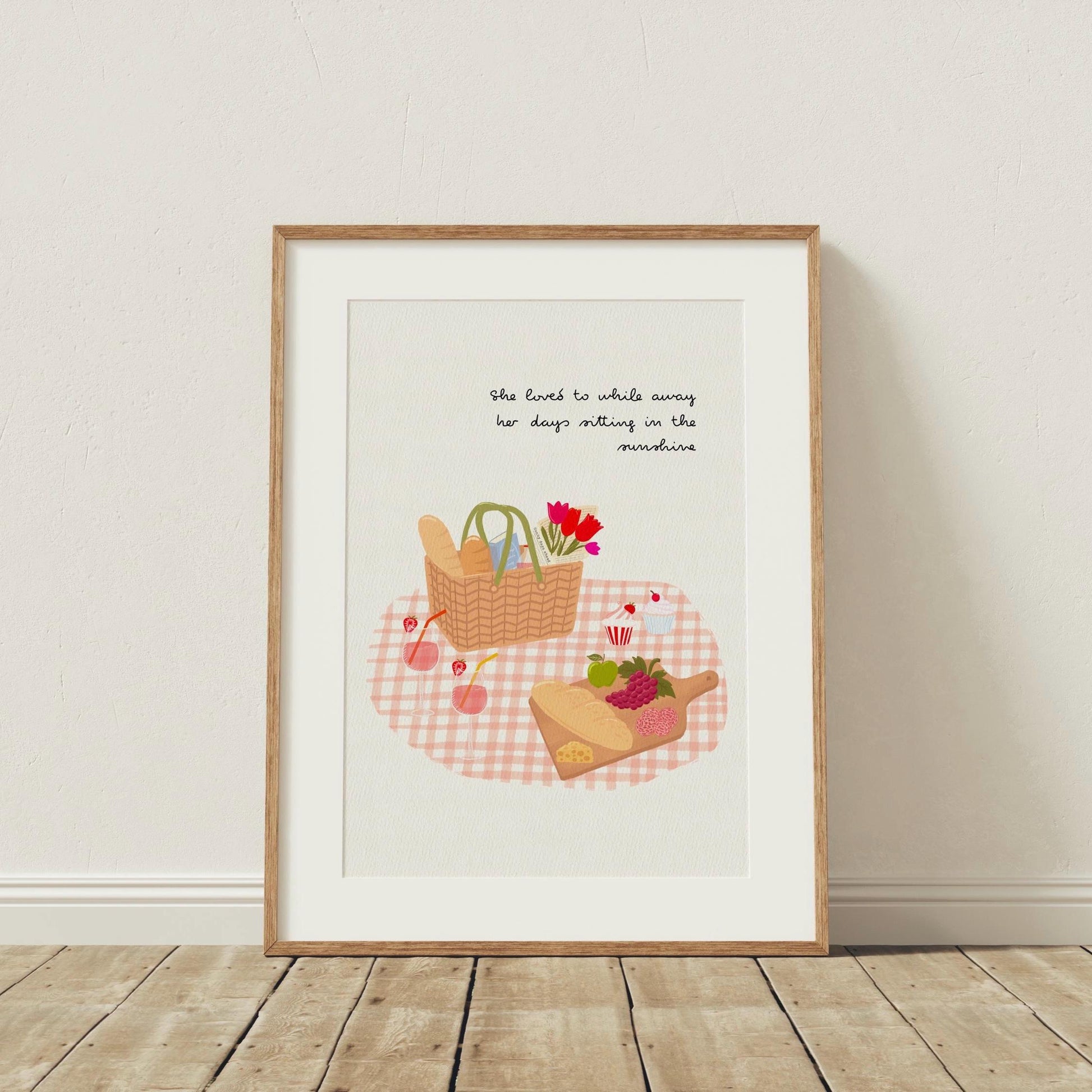 Framed artwork with a picnic scene and text on a white wall.