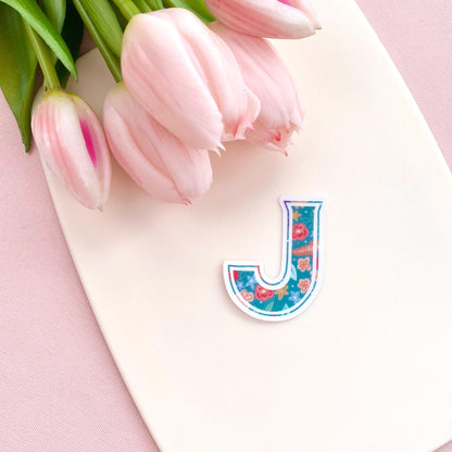 Letter 'J' sticker with pink tulips on a pink background