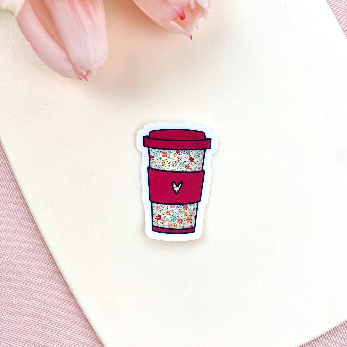 Sticker of a dark pink coffee cup with floral design on a white background