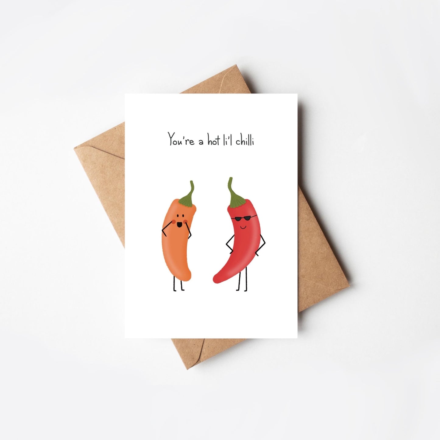 Card with cartoon red and orange  peppers and 'You're a hot li'l chilli' text and an envelope on a white background