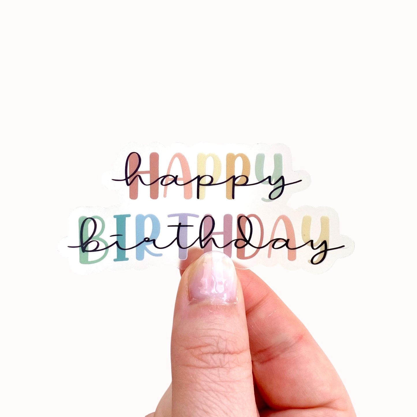 Colourful transparent 'Happy Birthday' sticker held by hand against a white background