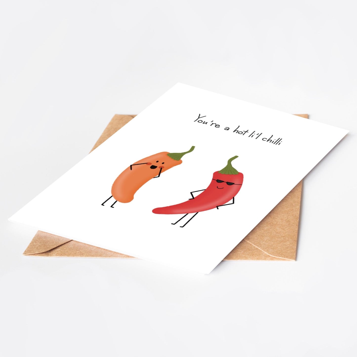 Card with cartoon red and orange  peppers and 'You're a hot li'l chilli' text and an envelope on a white background