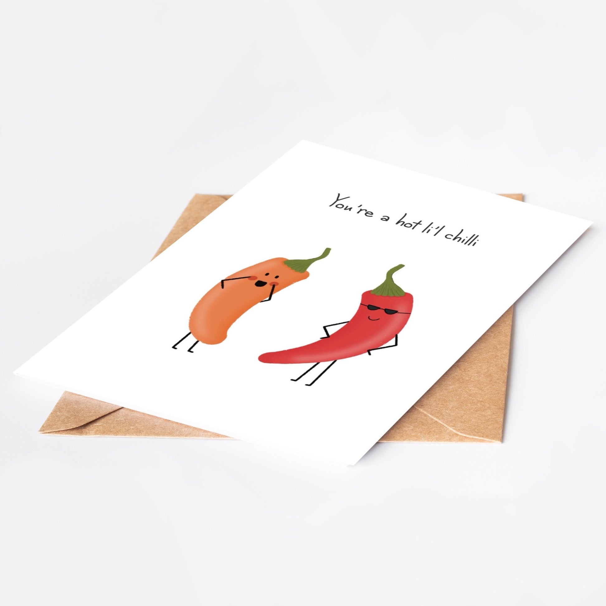Card with cartoon red and orange  peppers and 'You're a hot li'l chilli' text and an envelope on a white background