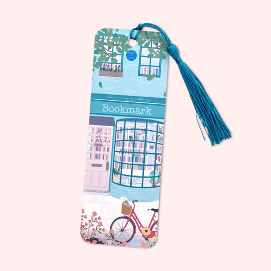 Bookmark with tassel featuring an illustration of a teal blue bookshop, a bicycle and flowers on a light pink background.