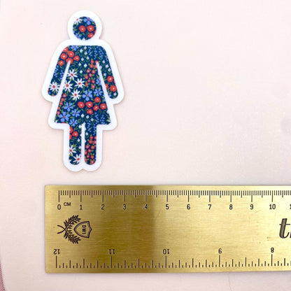 Floral-patterned woman sticker on a ruler for size reference