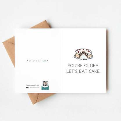Greeting card with cake illustration and text 'You're older. Let's eat cake.' on a white background.