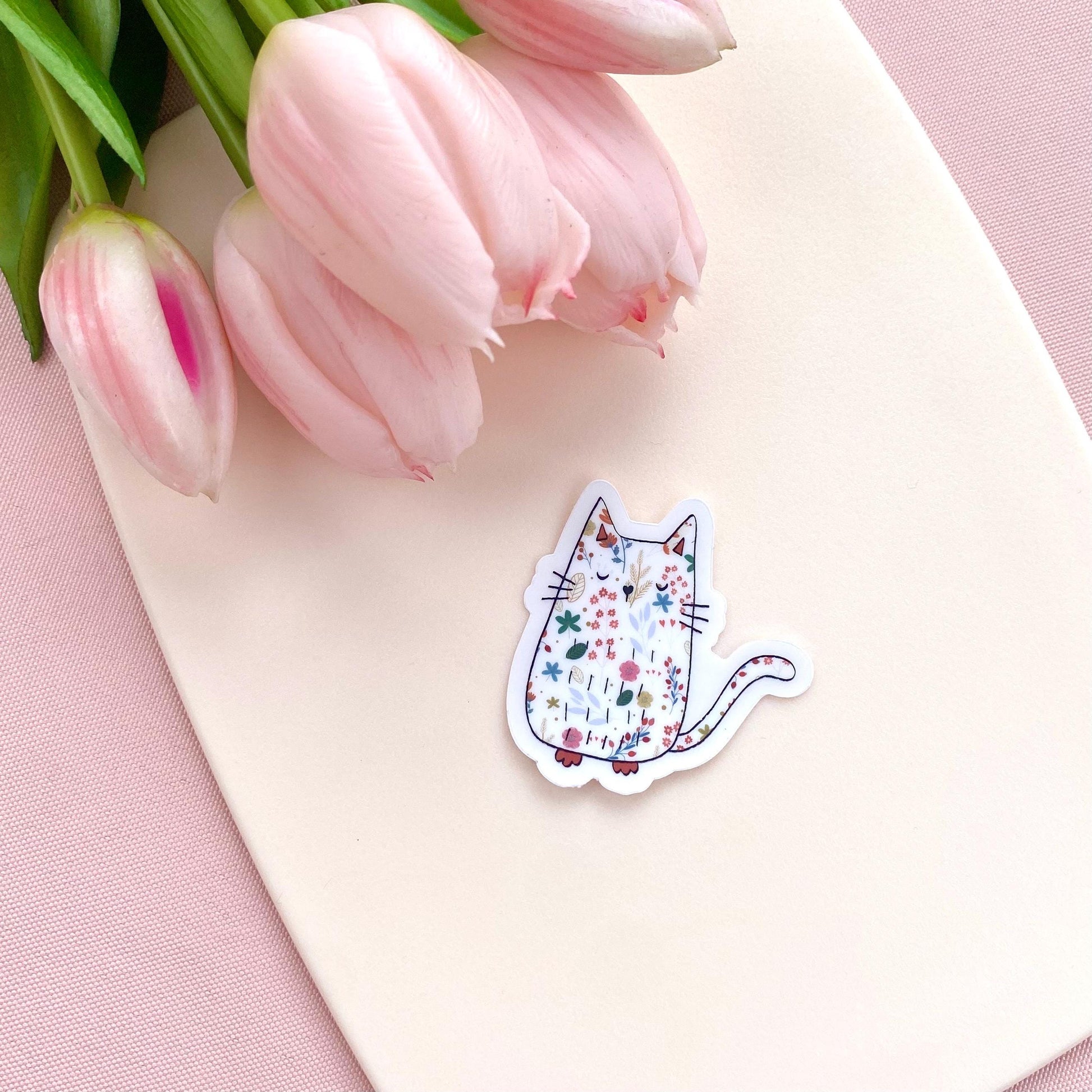 Decorative sticker of a cat with flowers on a pink surface with tulips.