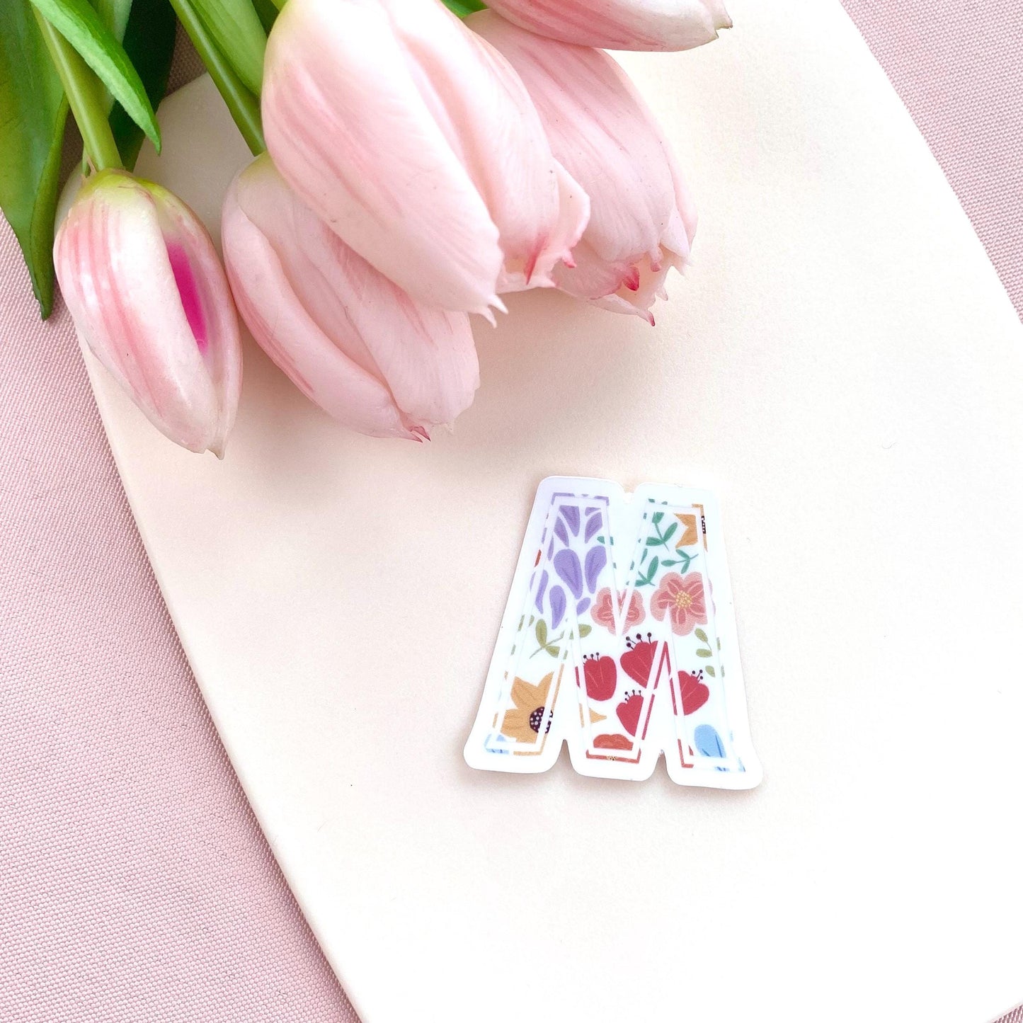 Decorative letter 'M' sticker with floral patterns on a white background with pink tulips