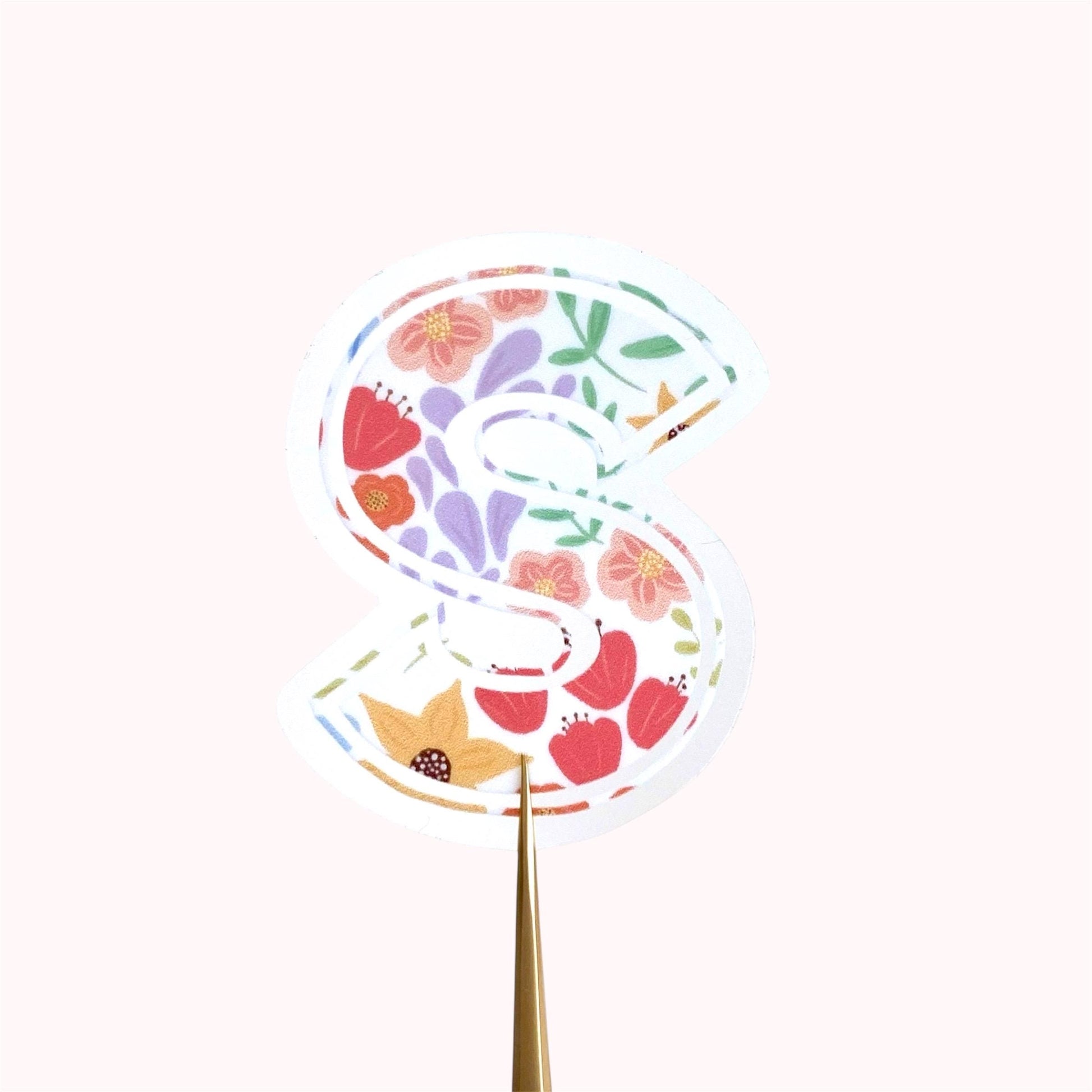 Decorative letter 'S' sticker with floral pattern on a white background