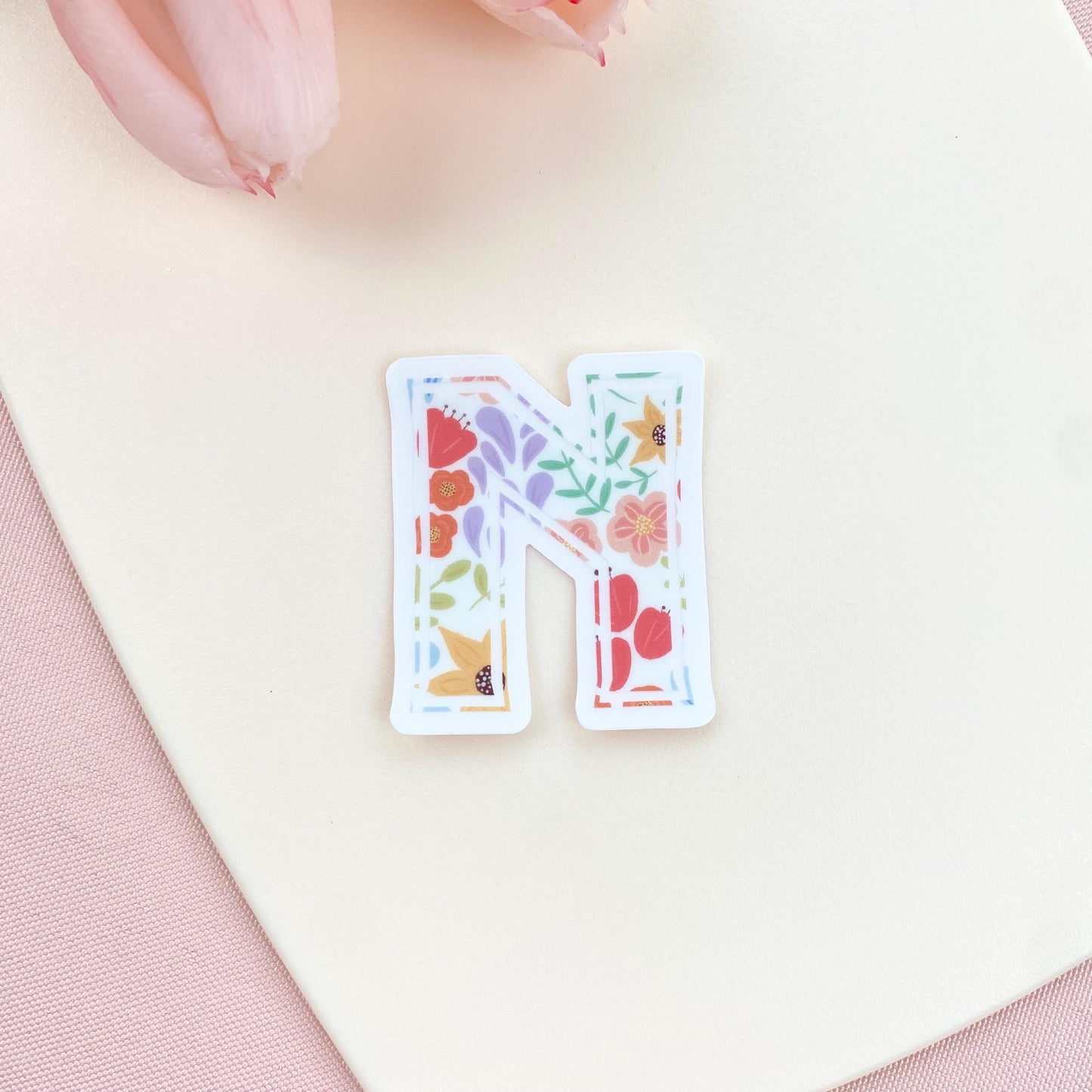 Floral letter 'N' sticker on a soft pink background