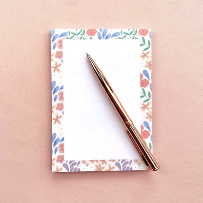 Floral notebook with a rose gold pen on a pink background