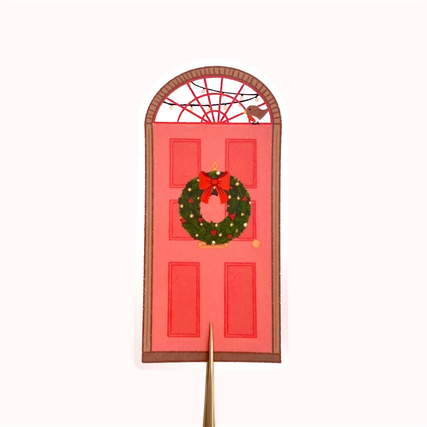Decorative sticker with a red door, wreath, robin and Christmas lights design on a white background.