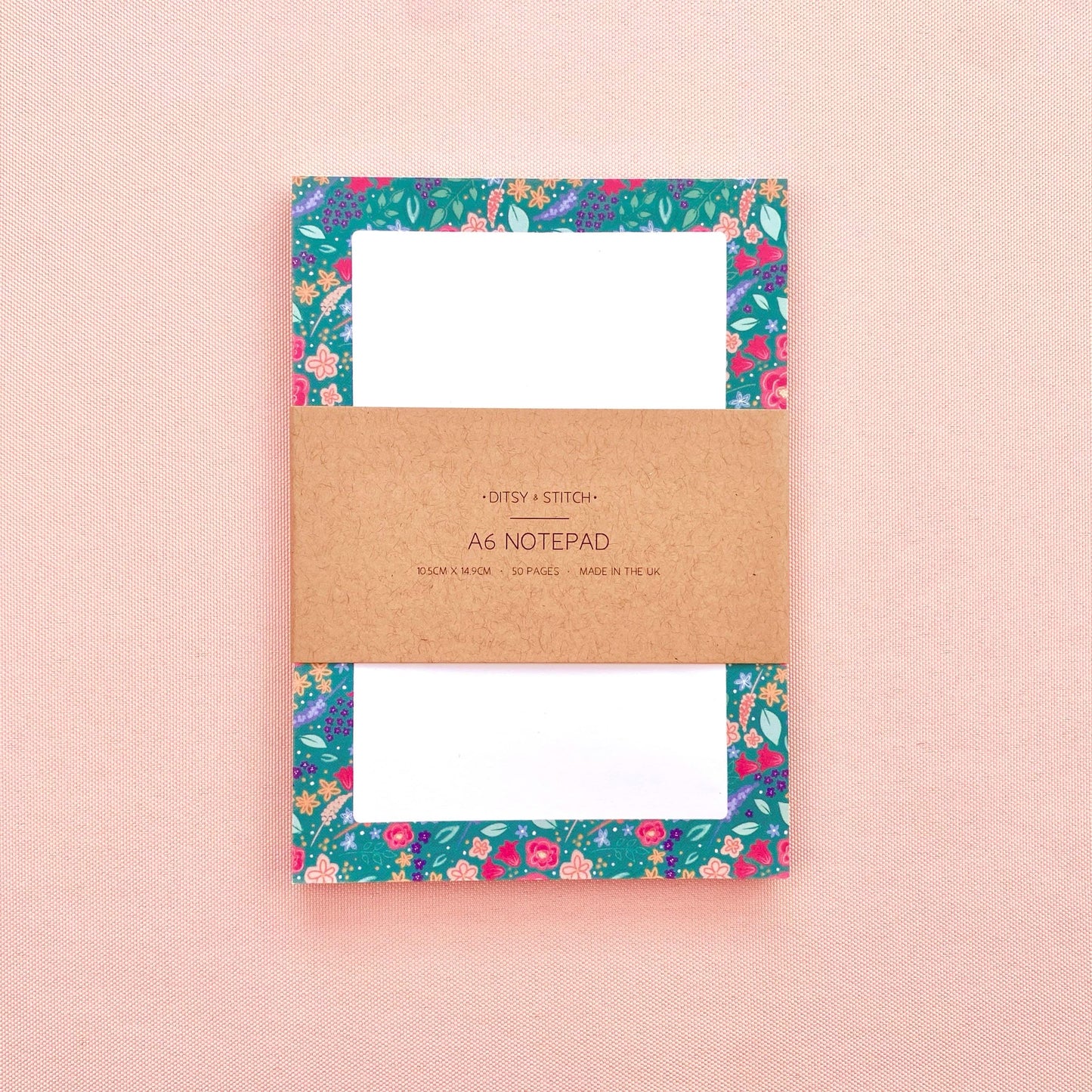 Floral notepad with a brown kraft paper label on a pink background