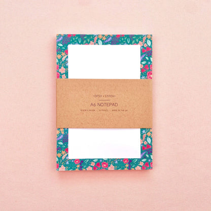 Floral notepad with a brown kraft paper label on a pink background