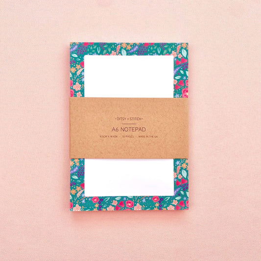 Floral notepad with a brown kraft paper label on a pink background