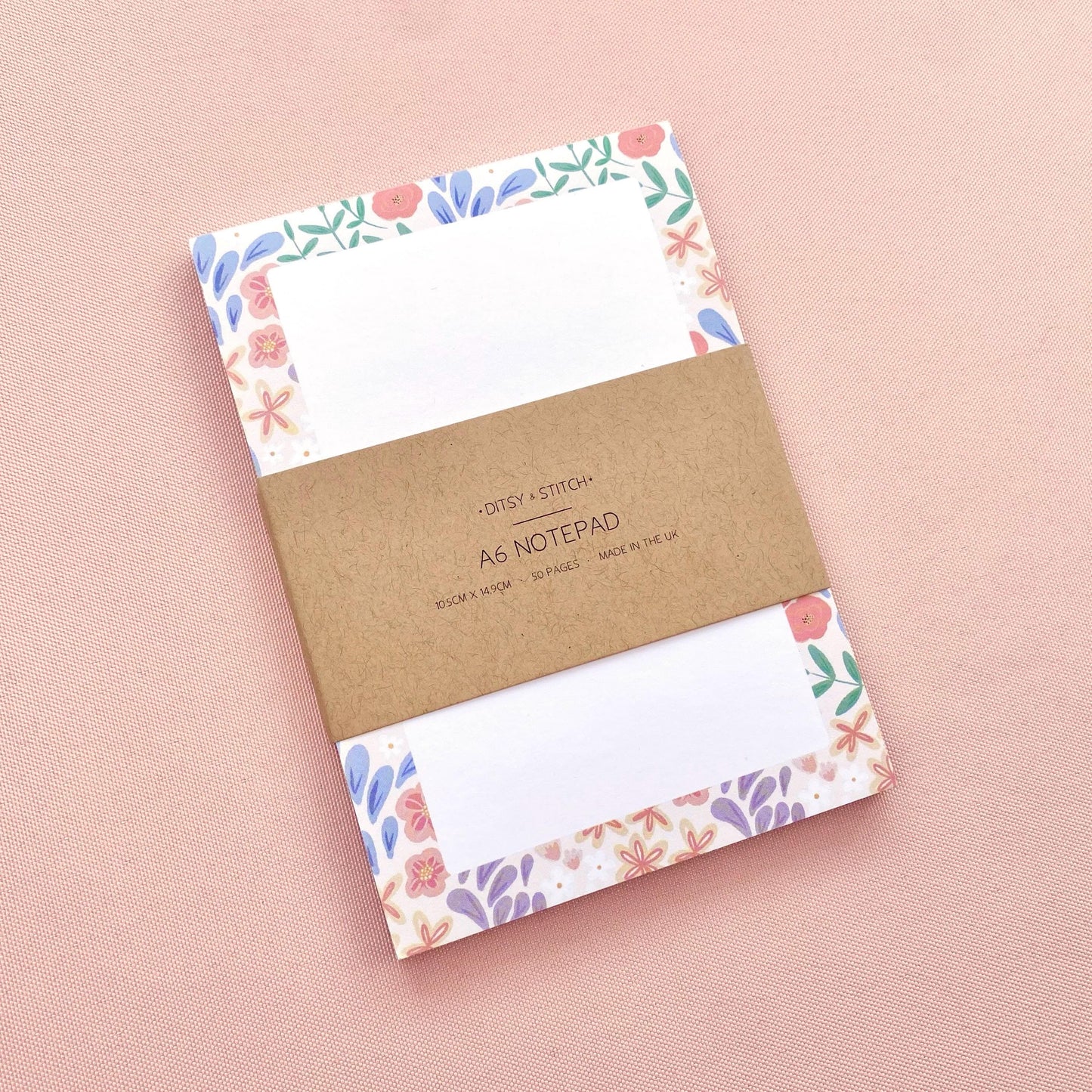 Notebook with floral border design on pink background