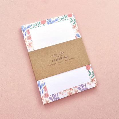 Notebook with floral border design on pink background
