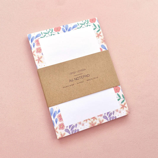 Notebook with floral border design on pink background