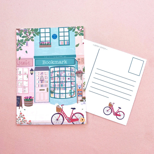Bookshop-themed postcard with a bicycle illustration on a pink background