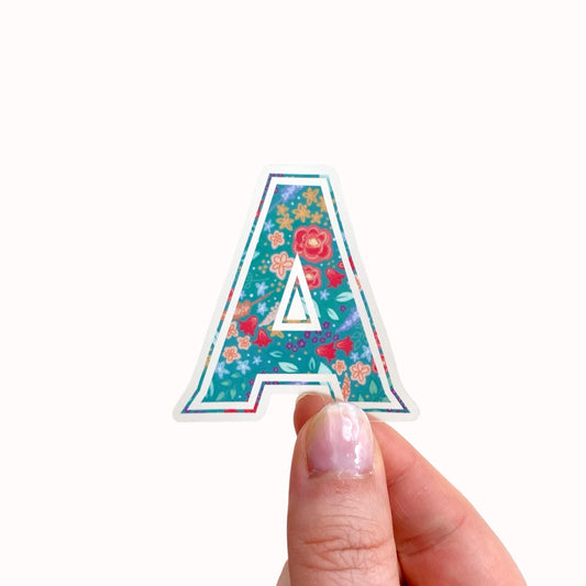 Colourful floral letter 'A' sticker held by a hand on a white background