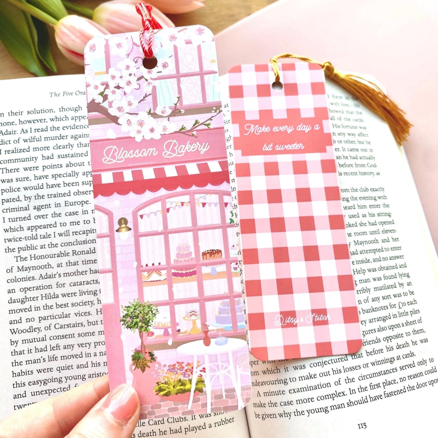 Two decorative bookmarks on a book with a pink and white checkered design and a bakery illustration.